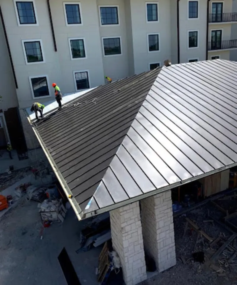 Crew installing standing seam metal roof panels on a commercial project in Snyderville